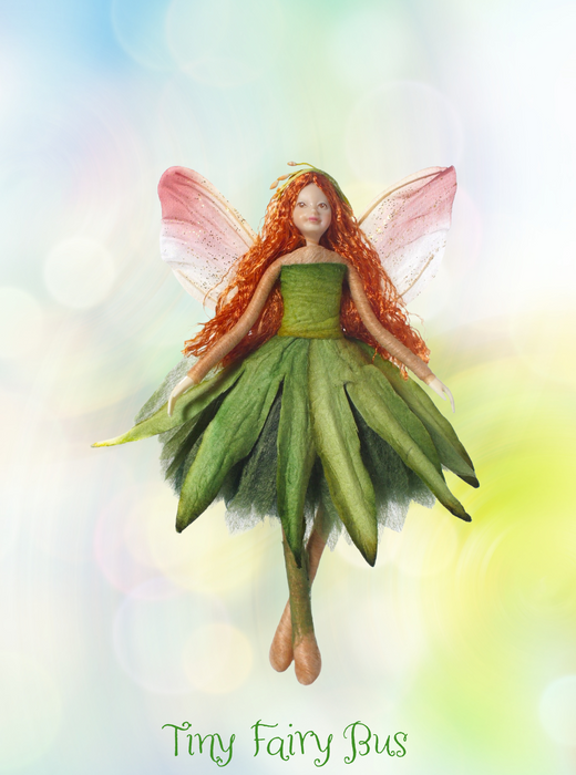 Fairy figurine with green dress and red hair on a colorful background